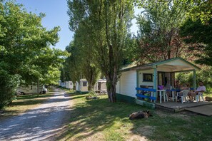 Un camping con casas móviles, una zona de estar cubierta y un perro acostado en el suelo.