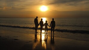 A sunset over the ocean with silhouettes of people standing on the beach. - Holiday home for 6 people in Wemeldinge (Wemeldinge)