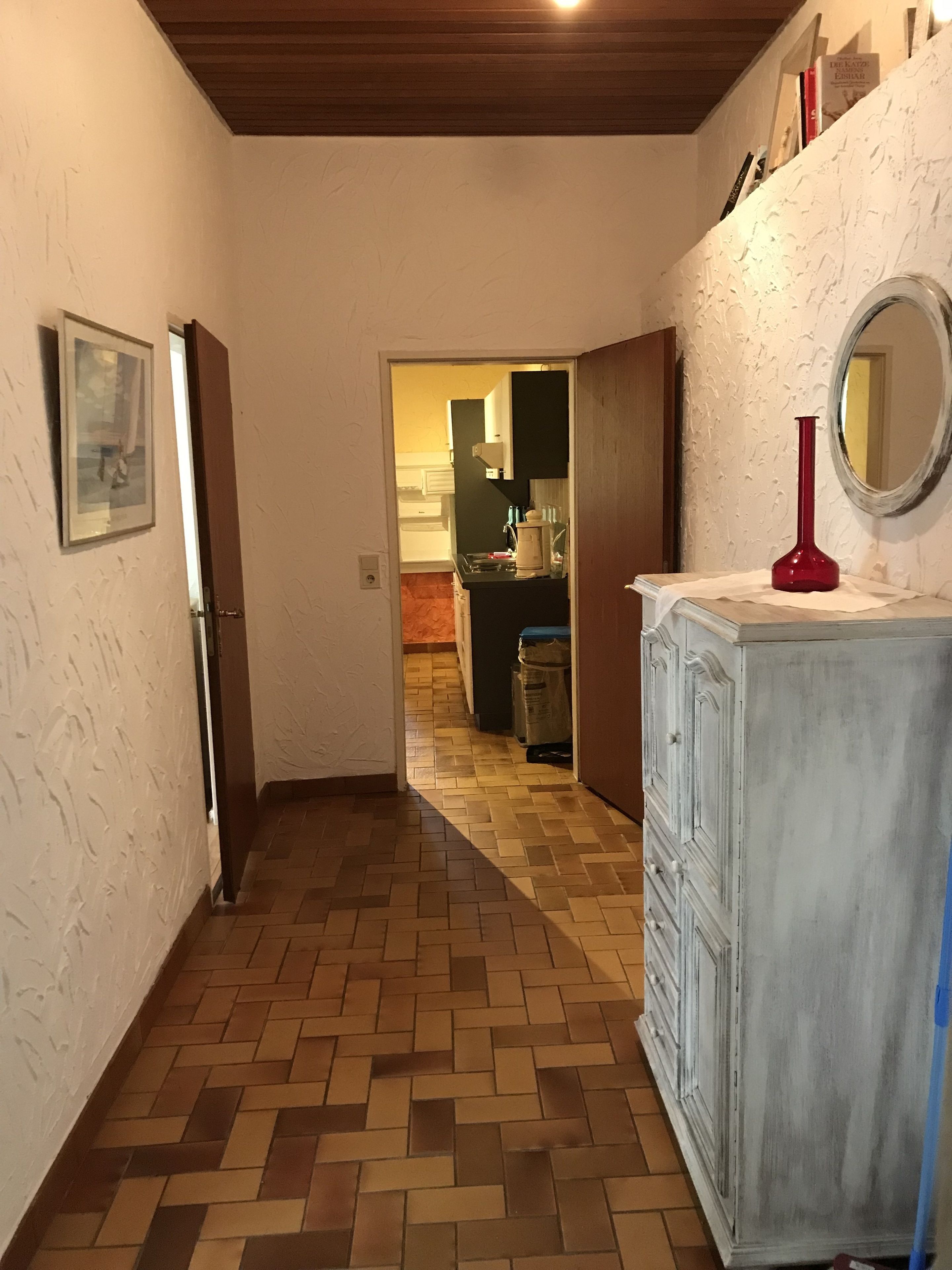 A hallway with a patterned floor leading to a kitchen area.