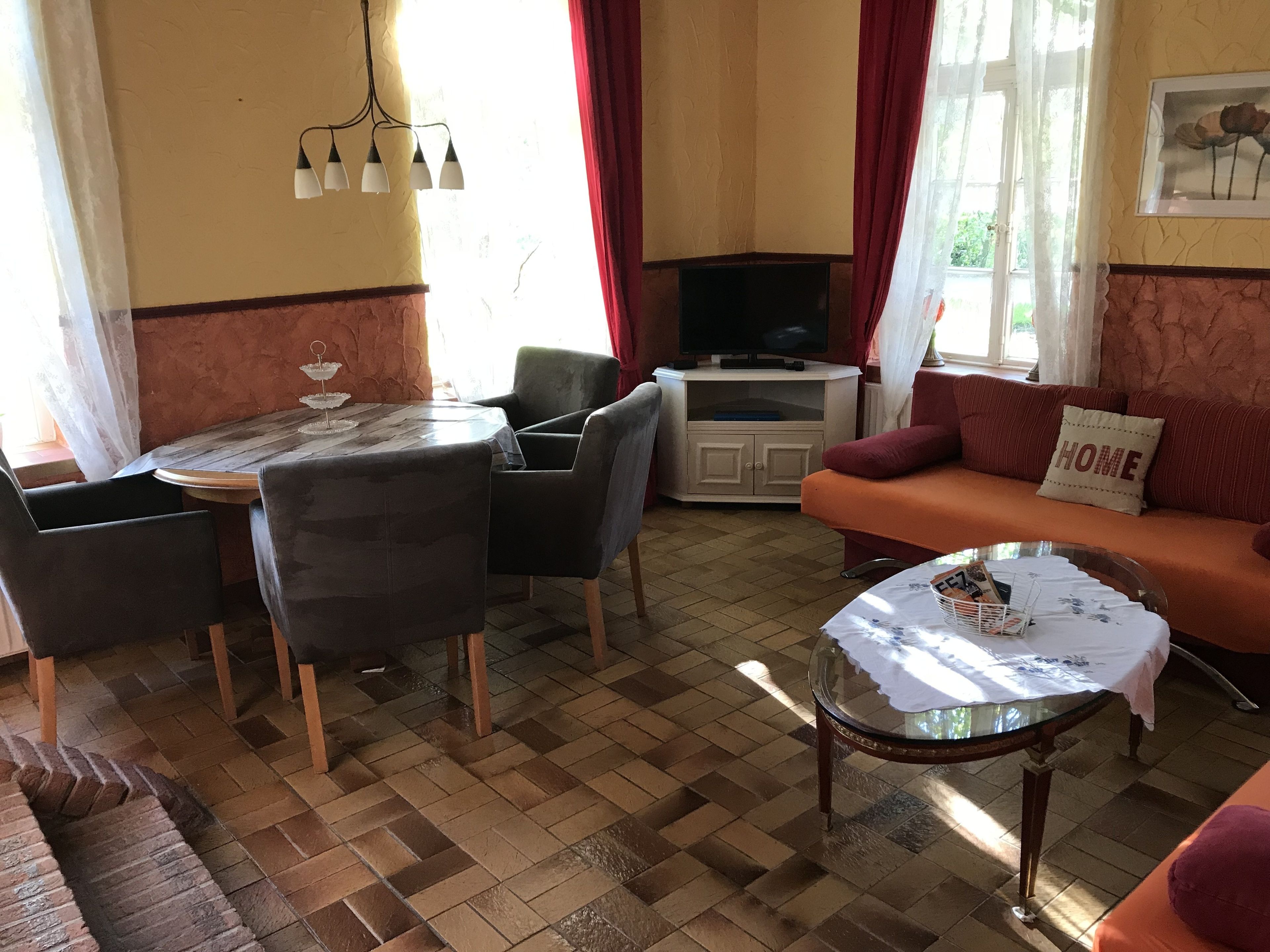 A living room with a wooden floor, a round glass coffee table, a sofa, and a television.