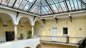 A multi-level atrium with a glass ceiling, white arches, and balconies with black railings.