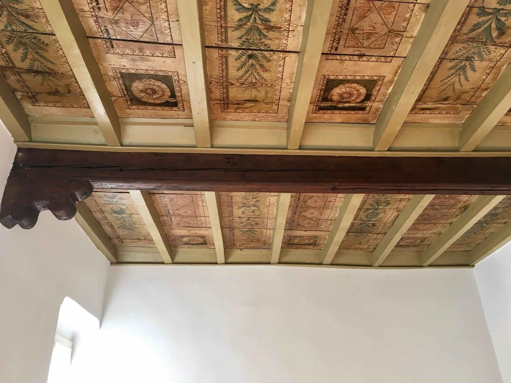 Une pièce dotée d’un plafond haut, orné de poutres en bois complexes et de panneaux décoratifs.