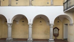 A courtyard with three arches, a fountain, and a clock.