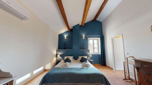 Un dormitorio con cama, lámparas de noche, ventana y cómoda.