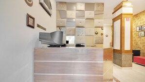 A reception area with a modern design, including a reception desk, a wall-mounted air conditioner, and a 'No Smoking' sign. - Itsy Hotels Auzone & Spa (Chandigarh)