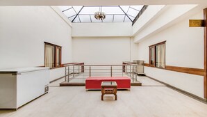 A spacious room with a skylight, a red bench, and a small table. - Itsy Hotels Auzone & Spa (Chandigarh)