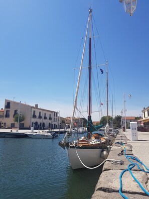 Enjoy a serene harbor scene with a sailing boat docked at the pier, surrounded by traditional Mediterranean-style buildings.
