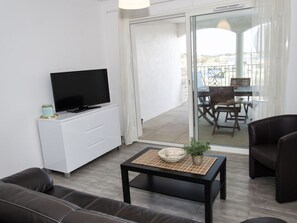Relax in this stylish living room with a flat-screen TV, comfortable sofa, and armchair, plus a balcony with a scenic view.