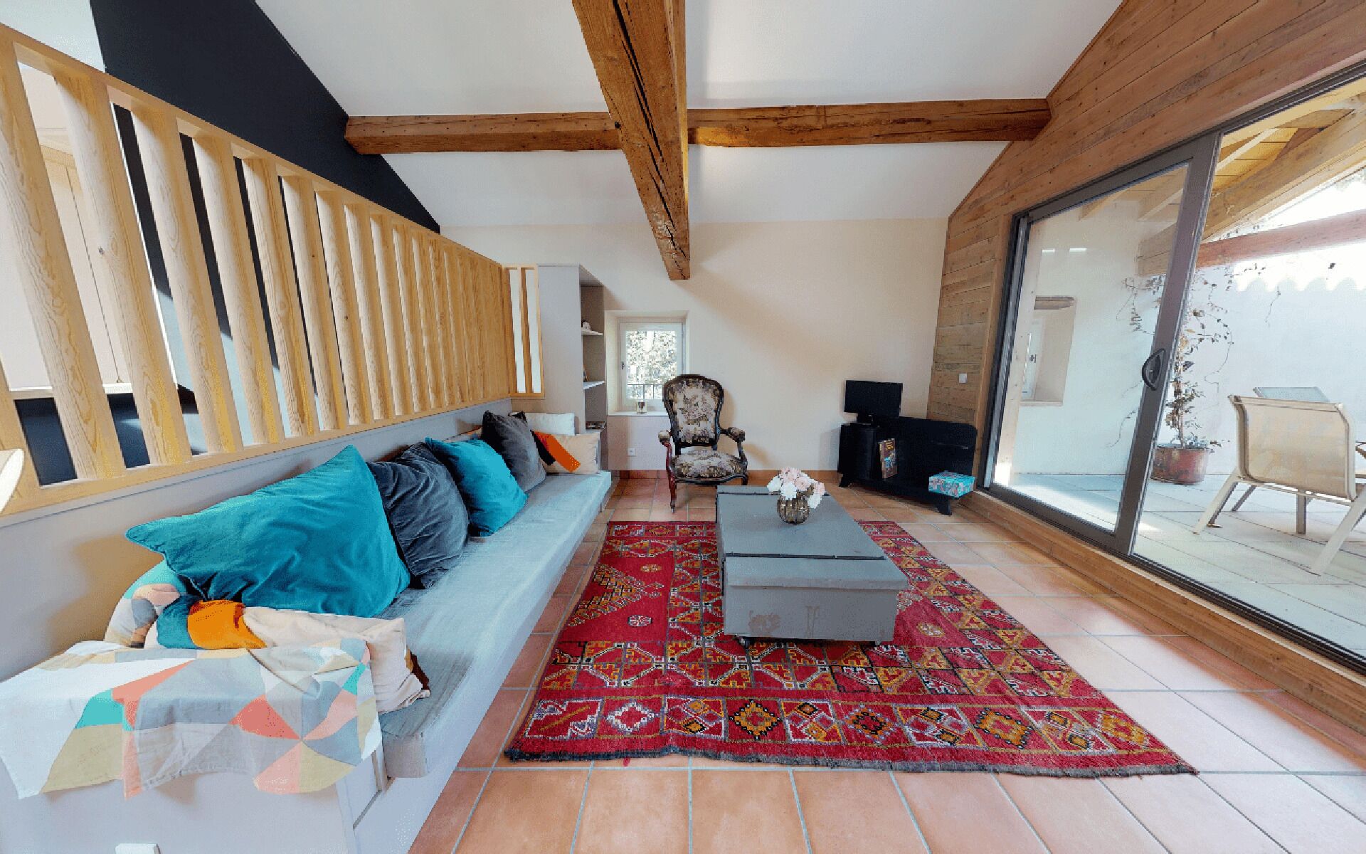 A spacious living area with a sofa, a patterned rug, and a large window.