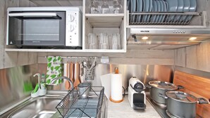 A kitchen with a built-in oven, a dish rack, a sink, and a stove with pots. - Camara Studio Mykonos (Mykonos)