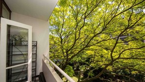 A balcony with a view of a lush green tree and a white railing. - Central Urban Oasis With Garden View & Swimming Pool (Cape Town)