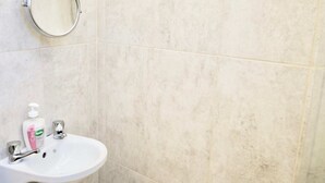 A bathroom with a white sink, a mirror, and a bottle of hand soap. - Cosy Studio in the Heart of Trendy Kemptown (Brighton)