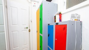 A hallway with lockers in green, blue, and red, a white door, and a fire extinguisher on a wall. - Cosy Studio in the Heart of Trendy Kemptown (Brighton)