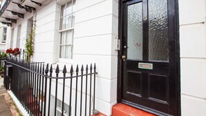 A white building with a black door and a black metal fence. - Cosy Studio in the Heart of Trendy Kemptown (Brighton)