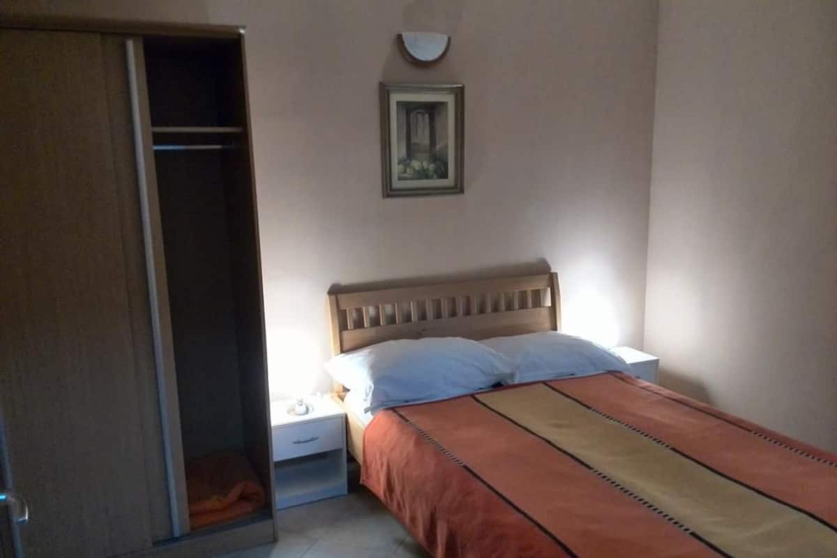 A bedroom with a bed, nightstand, and wardrobe.