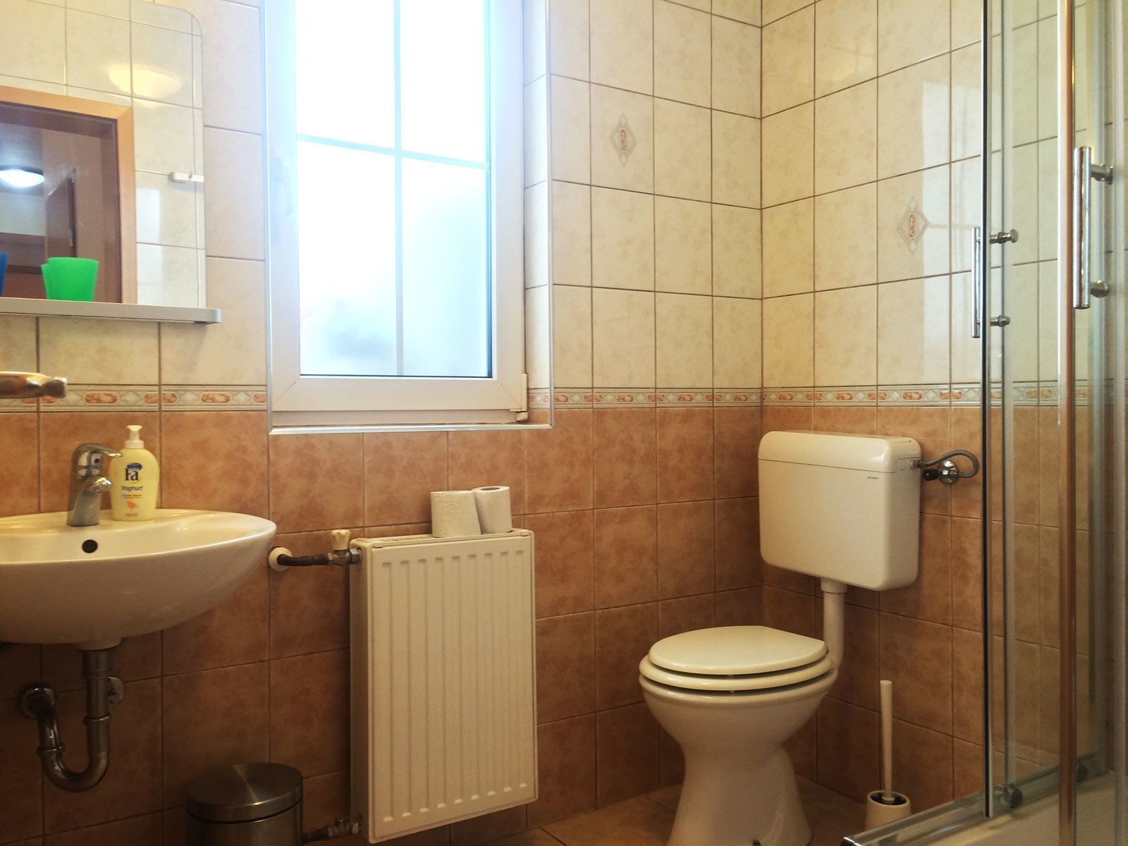 Un baño con lavamanos, inodoro y cabina de ducha de vidrio.