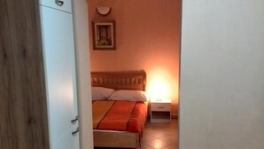 A bedroom with a bed, bedside table, and a wardrobe. - Apartments Bogdanovic (Maribor)