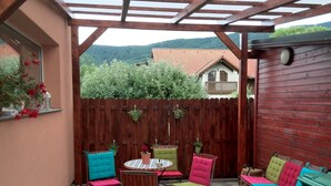 A patio with a round table and colorful chairs, a barbecue grill, and a wooden fence. - Apartments Bogdanovic (Maribor)
