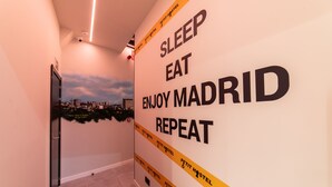 Un pasillo con una pared que muestra el texto "SLEEP EAT ENJOY MADRID REPEAT" y vistas de la ciudad.