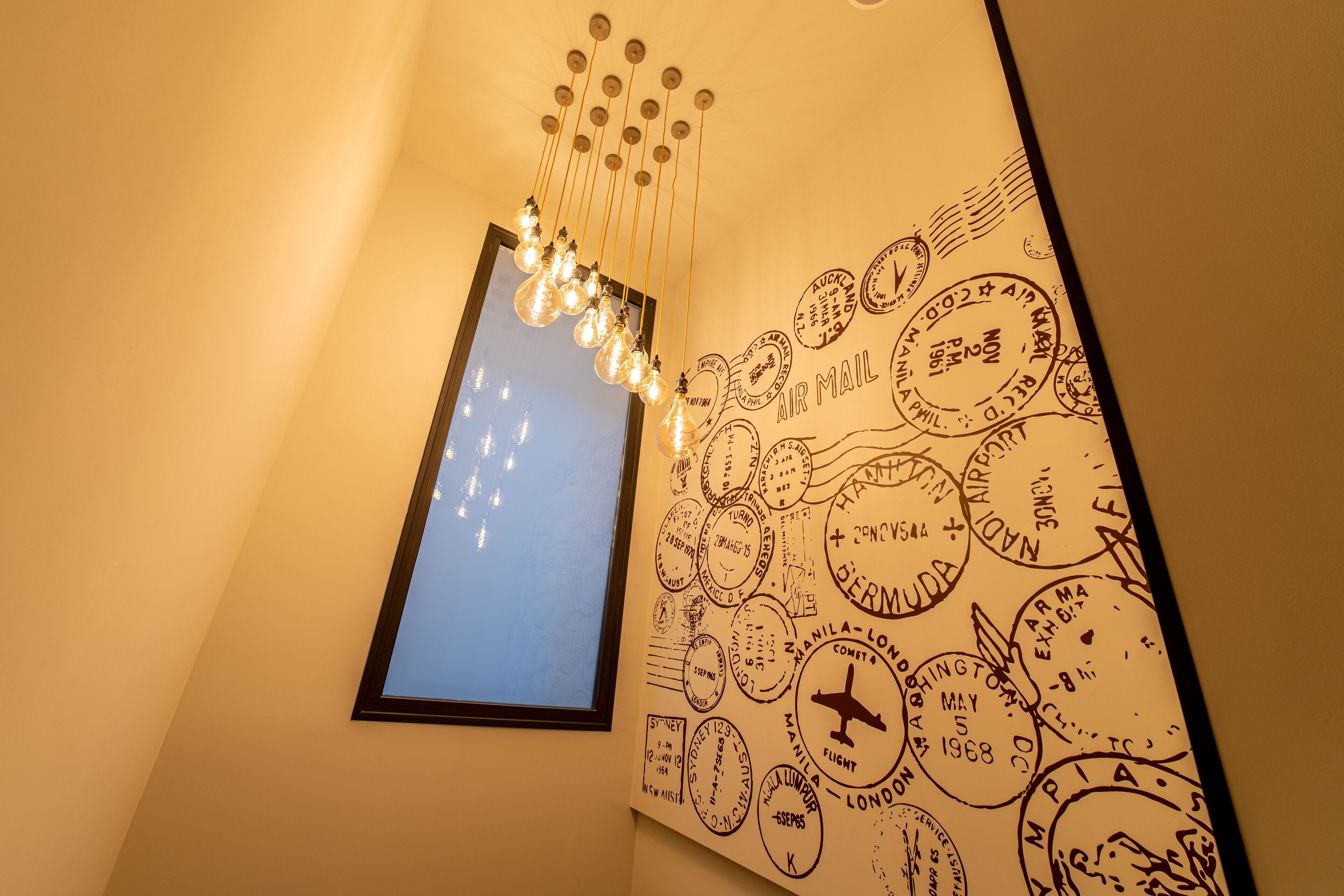 Una pared con una colección de sellos antiguos y un colgador de luz.