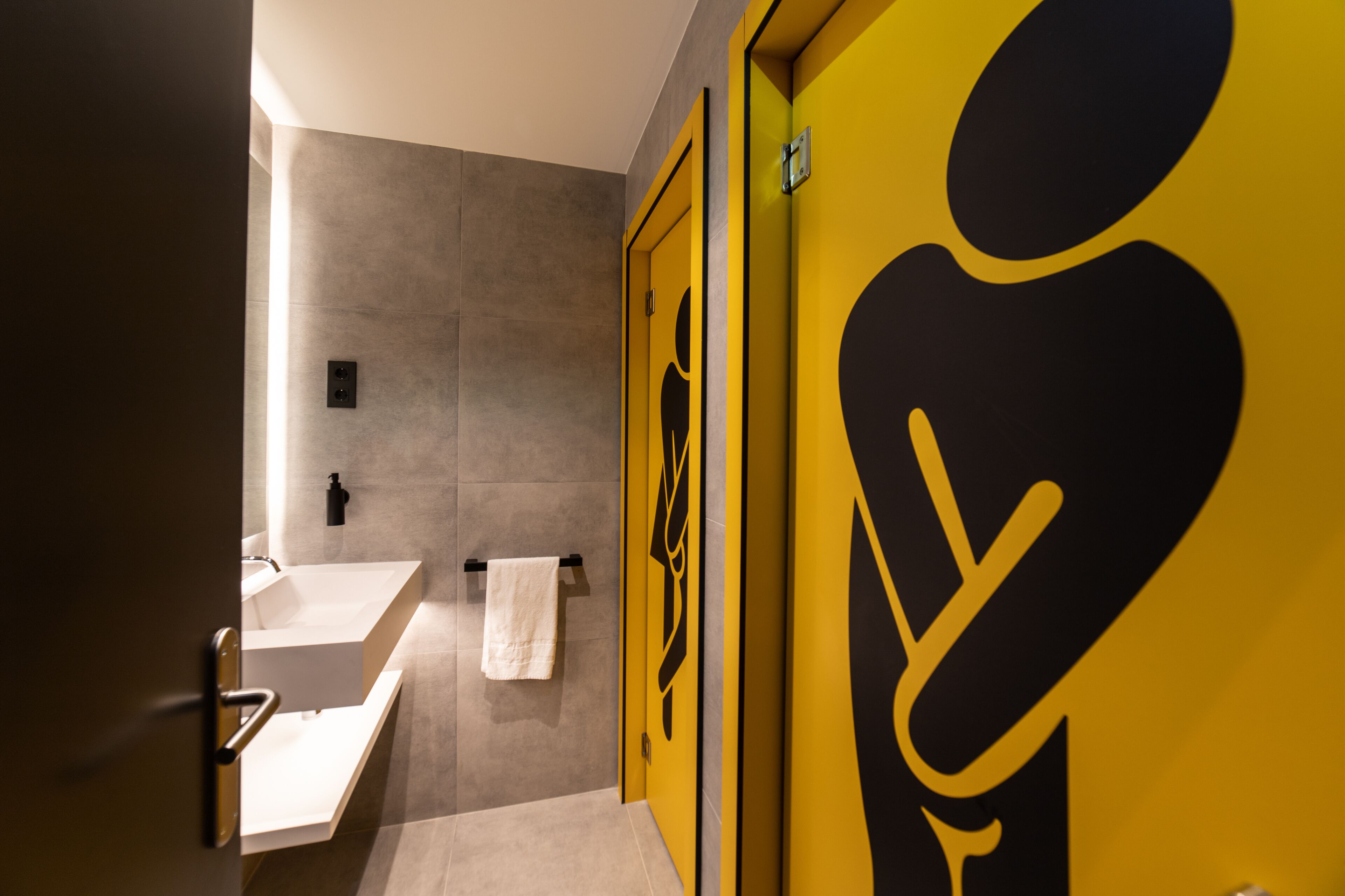 Un bany modern amb un mirall gran, un lavabo i una tovallola penjada a la paret.