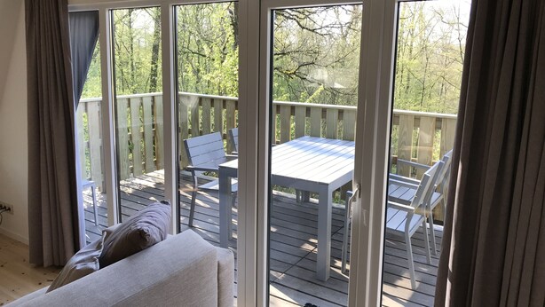A room with a sliding glass door leading to an outdoor deck with a table and chairs. - Orava Durbuy (Durbuy)