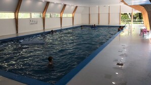 An indoor swimming pool with clear water, wooden beams on the ceiling, and a tiled floor. - Orava Durbuy (Durbuy)