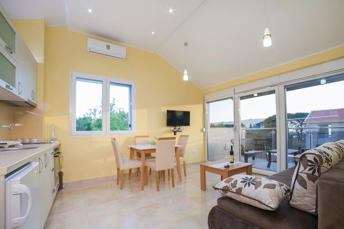 Una cocina moderna con comedor, sofá y televisor.