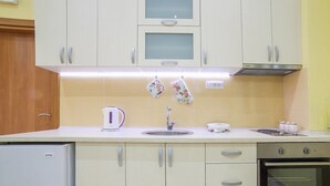 Una cocina con armarios blancos, un fregadero, un hervidor y una estufa.