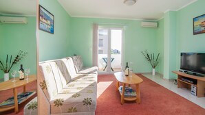 Una sala de estar con sofá, mesa de centro, televisor y balcón con vistas.