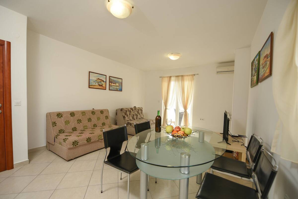 Una sala de estar moderna con una mesa de comedor de vidrio, dos sofás y un televisor.