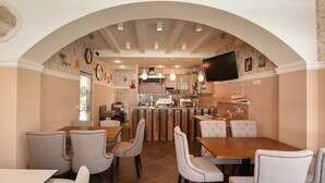 Comedor con barra central, diversas opciones de asientos y área de cocina visible a través de un arco.