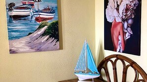 A room with a wooden dresser, a small sailboat model, and a pink vase.