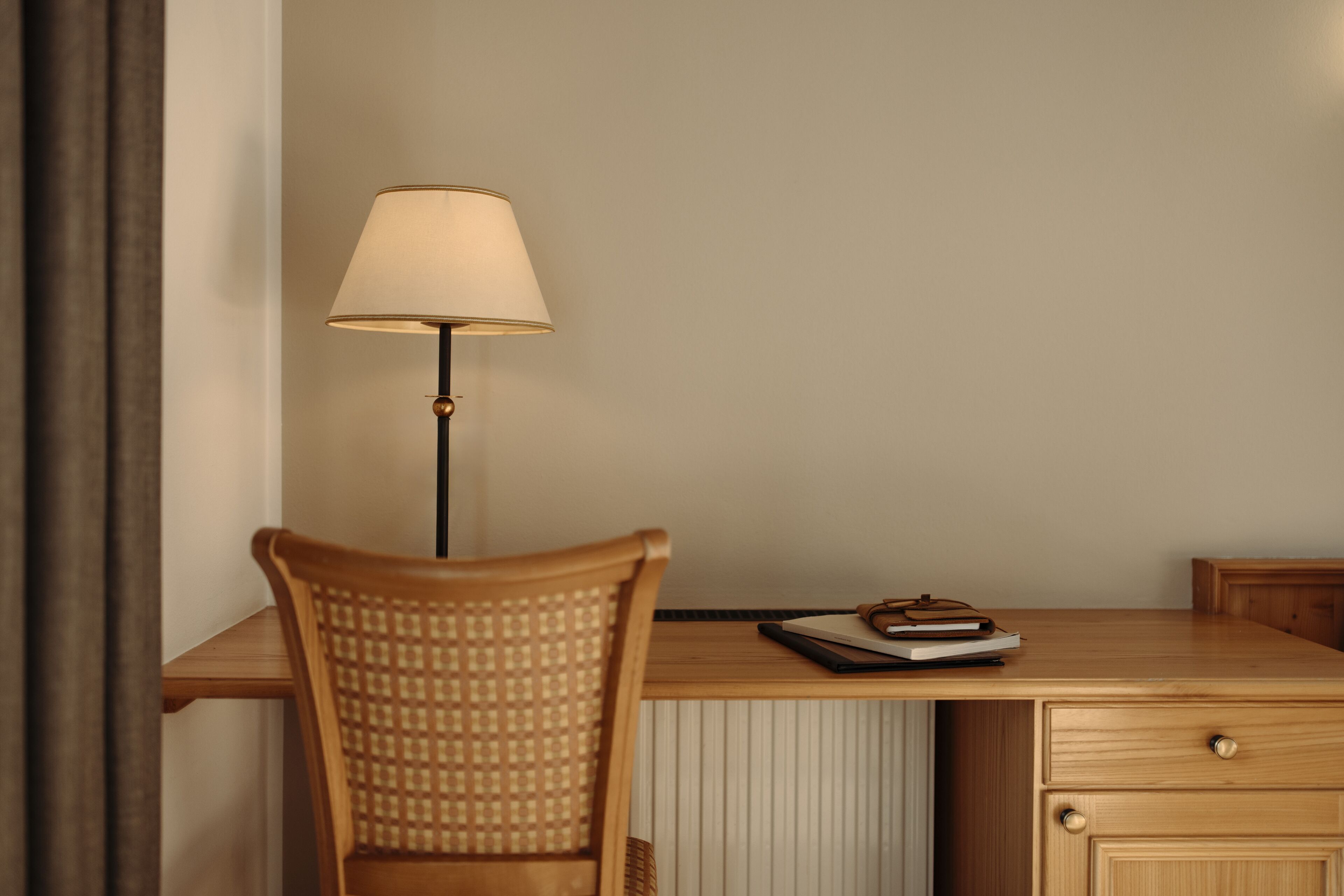 A wooden desk with a lamp, a chair, and a notebook.