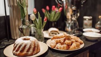 A buffet table with a bundt cake, croissants, and a plate of sushi.