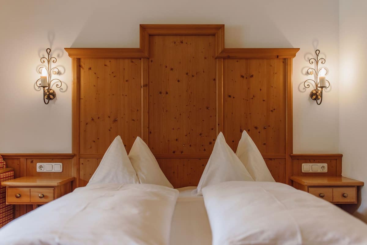 Un dormitorio con cabecera de madera, dos mesitas de noche y apliques de pared.