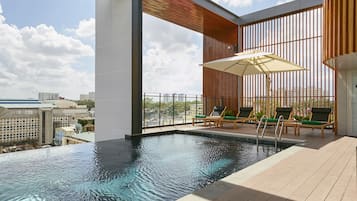 Una piscina al aire libre, sombrillas, sillones reclinables de piscina