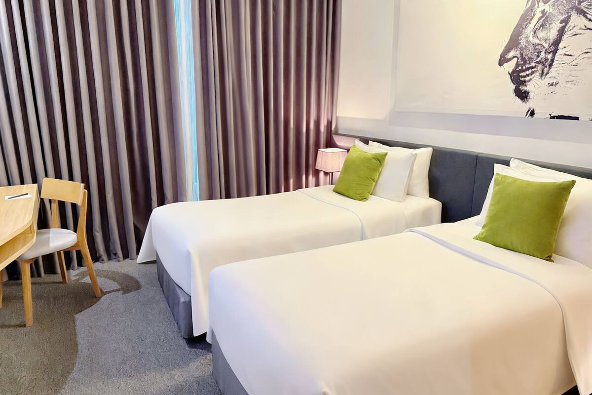 A hotel room with two beds, a desk, and a chair.