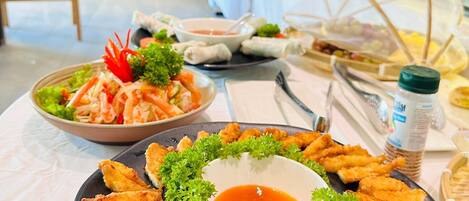 A buffet table with various dishes including spring rolls, fried items, and a bowl of soup.
