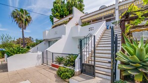 A modern house with a white exterior, a gated entrance, and a staircase leading to the upper floor.