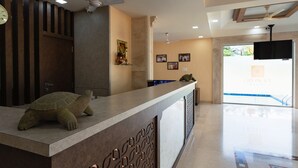 A reception desk with a turtle sculpture, ceiling fans, and framed pictures on the wall. - City Palace Resort (Mawal)
