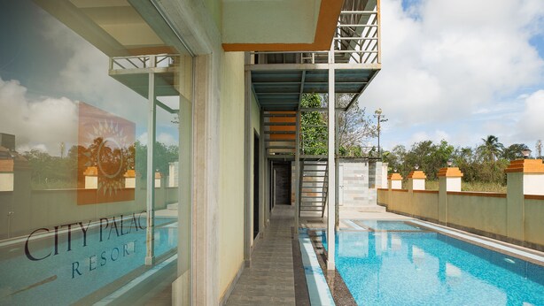 A swimming pool area with a glass wall displaying the text "CITY PALACE RESORT". - City Palace Resort (Mawal)