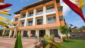 A multi-story hotel with a flat roof, large windows, and a paved entrance area with potted plants. - City Palace Resort (Mawal)
