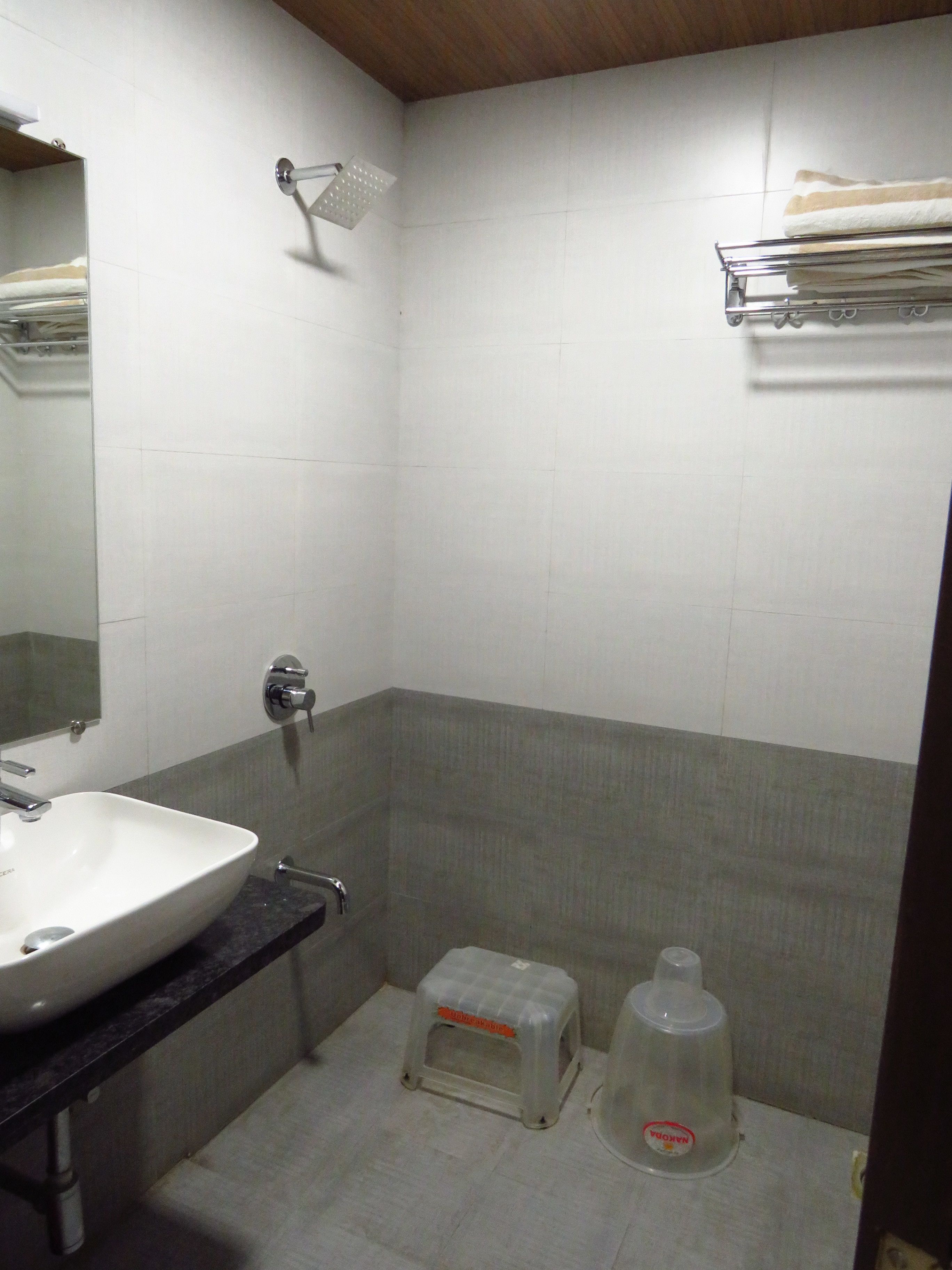 A bathroom with a white sink, a mirror, a shower, and a towel rack.