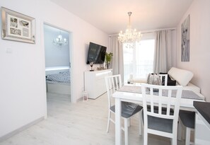 Una sala de estar moderna con comedor, televisor y candelabro.
