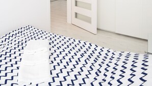 A modern interior with a white door, a chandelier, and a patterned rug.