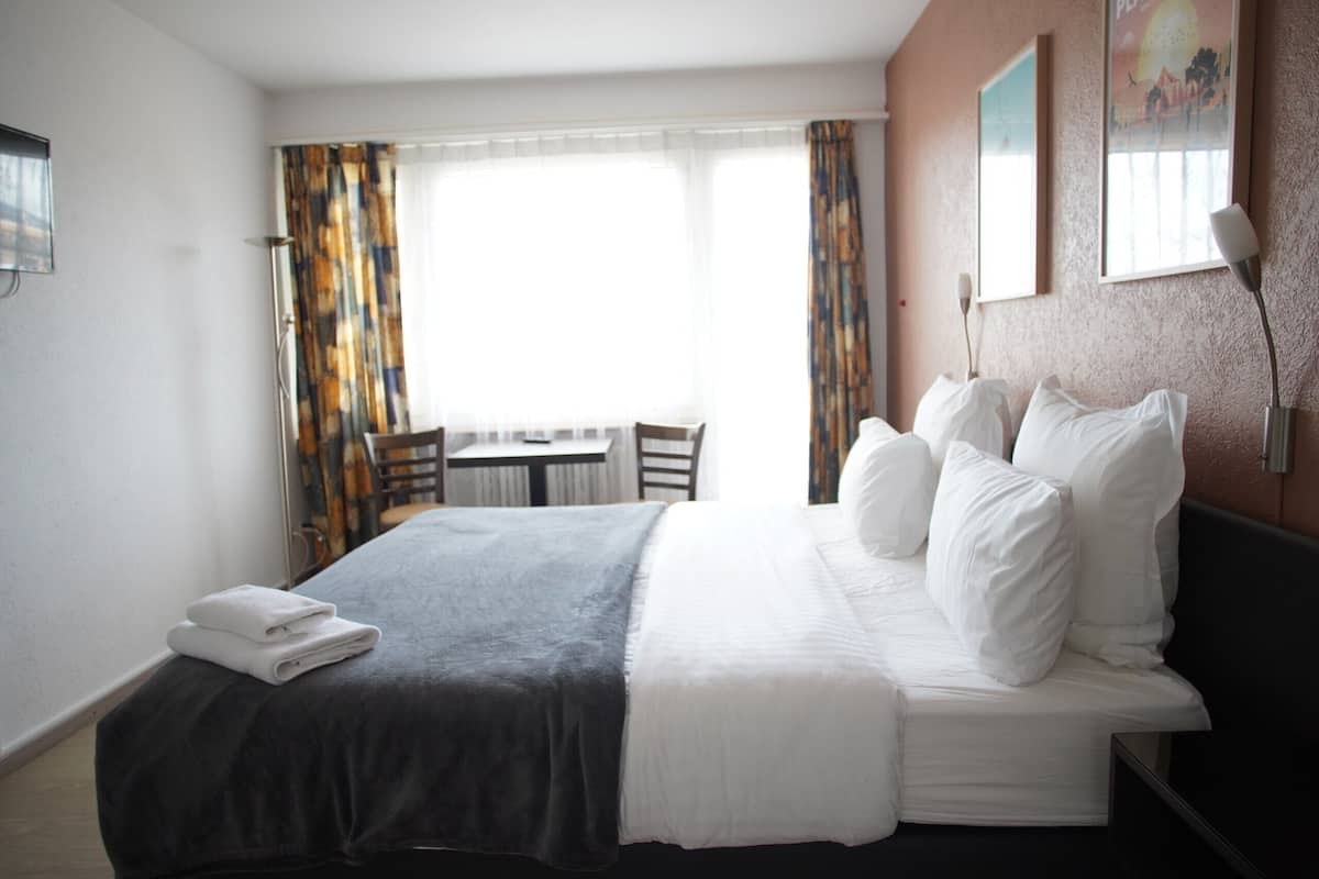 Una habitación de hotel con una cama, un escritorio y una silla.