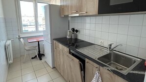A modern kitchen with wooden cabinets, a black countertop, and a stainless steel sink. - PRIMADOM Aparthotel (Geneva)