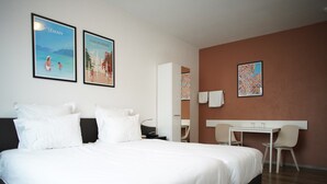 A hotel room with a large bed, a desk, and two chairs. There are two framed pictures on the wall. - PRIMADOM Aparthotel (Geneva)