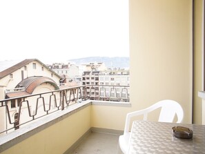 A balcony with a view of buildings and a table with a chair. - PRIMADOM Aparthotel (Geneva)